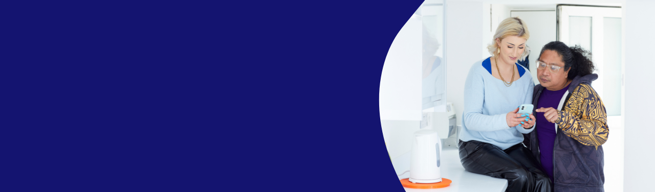 A dark blue banner with an image of a woman sitting on a bench with a man beside her looking over her shoulder scrolling through her mobile phone together