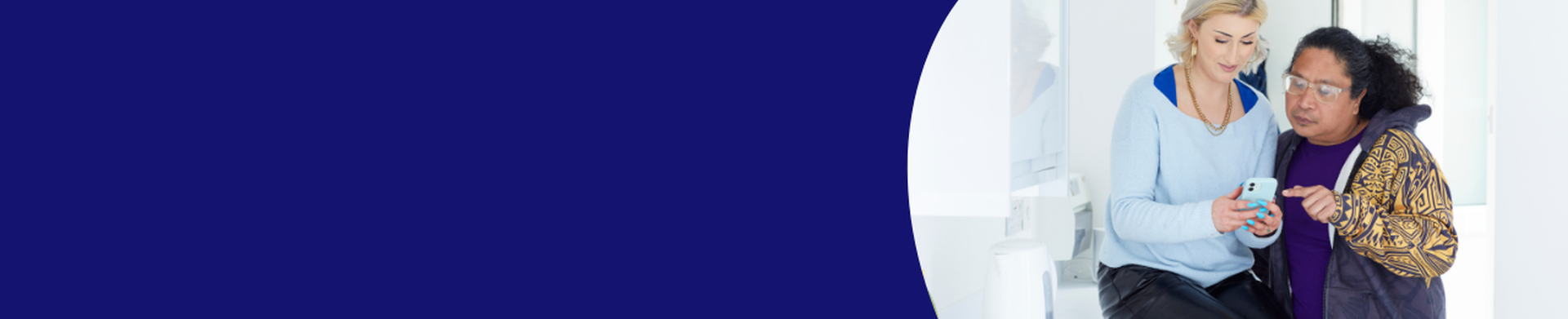 A dark blue banner with an image of a woman sitting on a bench with a man beside her looking over her shoulder scrolling through her mobile phone together